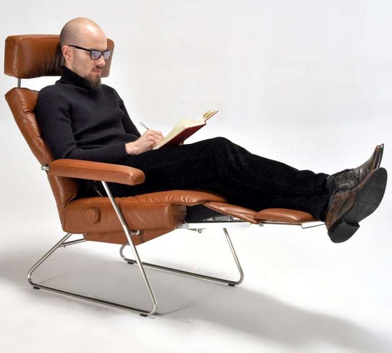 man in brown recliner reading a book
