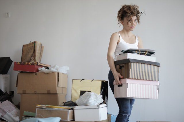  A woman carrying several boxes away from a pile of other boxes 