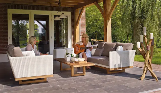 Two women sitting outdoors, playing the guitar.