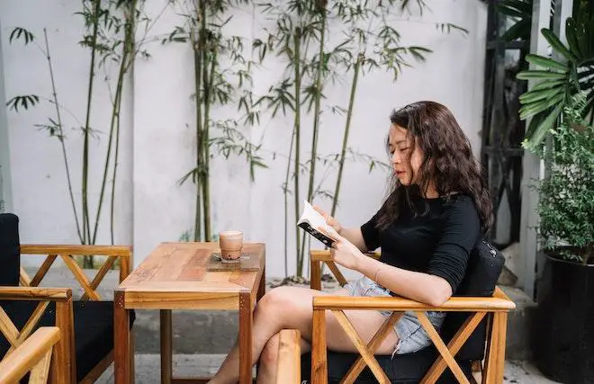 A woman reading while sitting in a high-quality wooden chair.