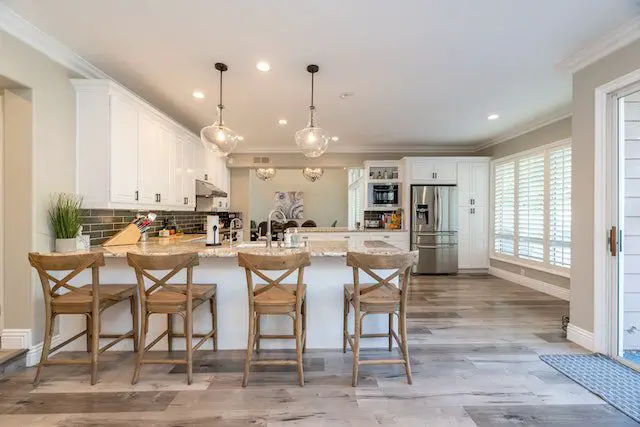 A kitchen with wooden chairs and white cupboards