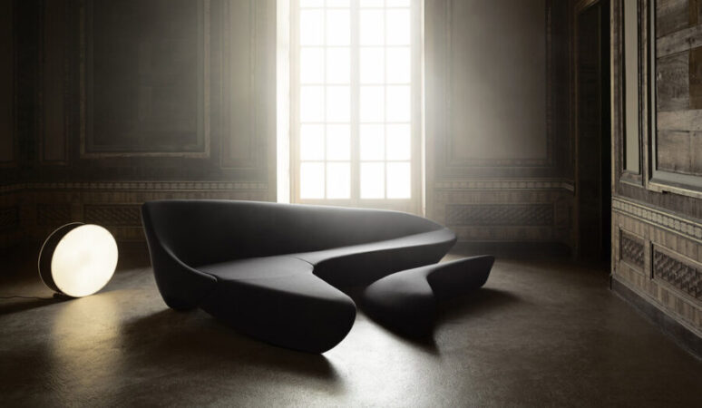 A black Moon System sofa by Zaha Hadid in a room with a shining light.